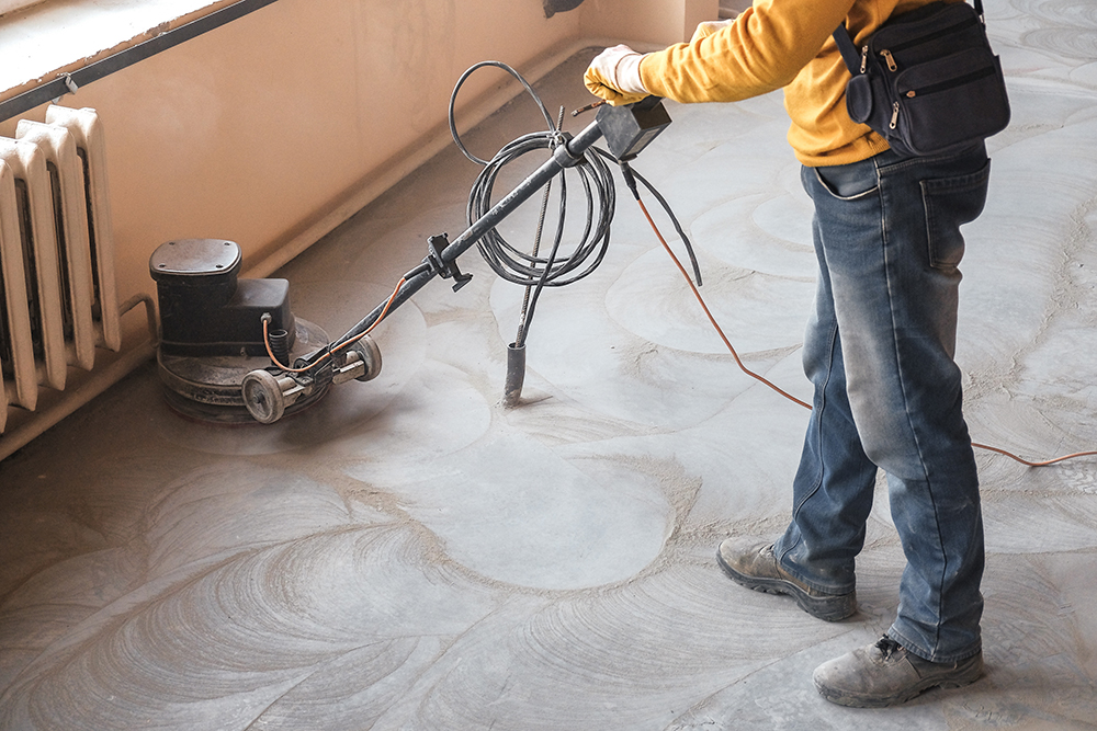 workers grind the concrete floor at the construction site